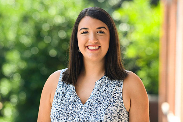 Mollie Martin smiling with a greenery background