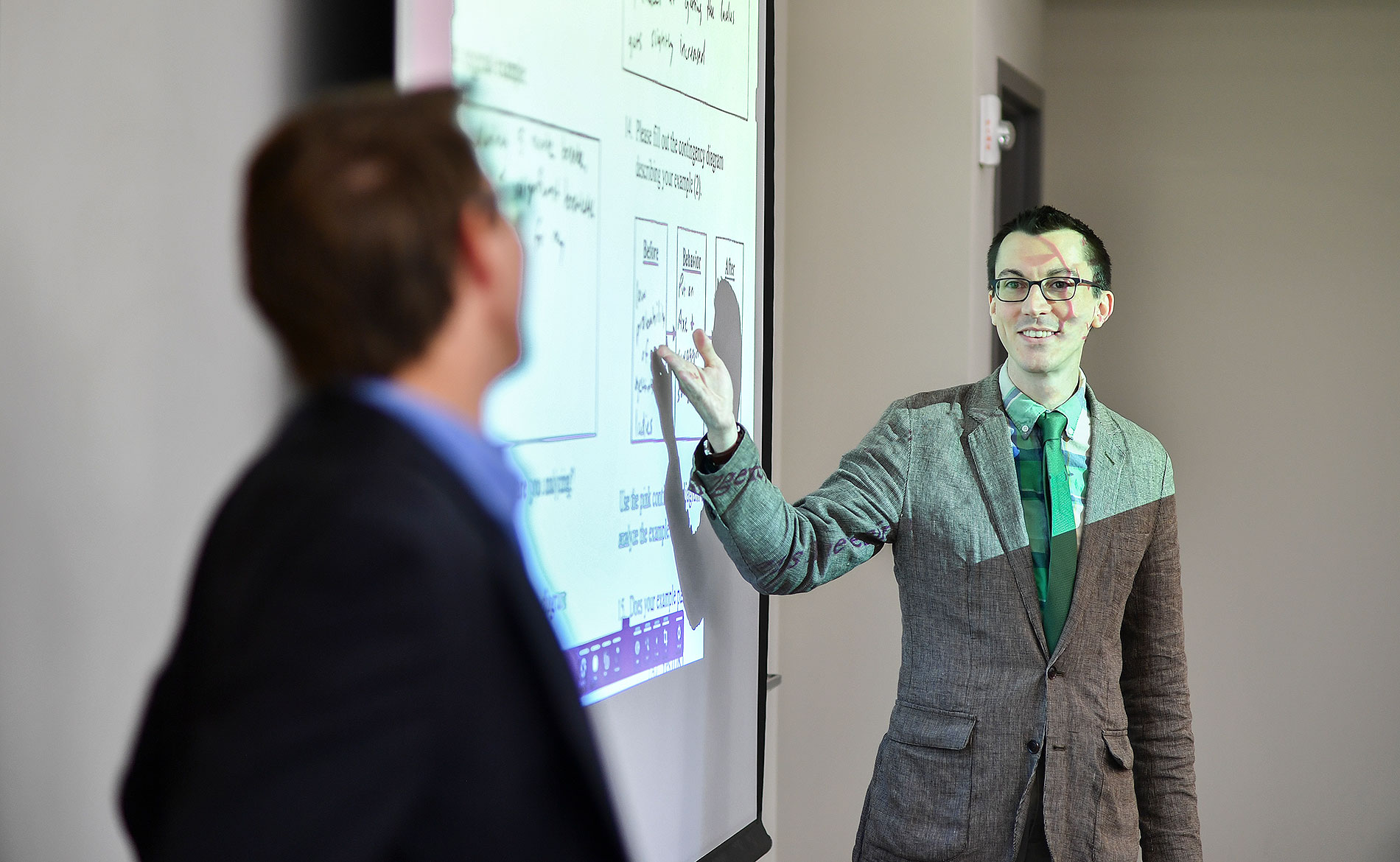 two students presenting and pointing at a projection screen