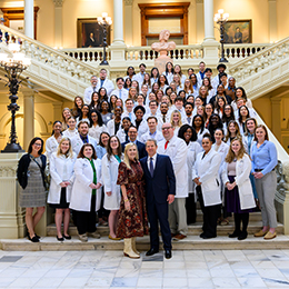 PA students and faculty in white lab coats standing on the steps of the Capitol Building