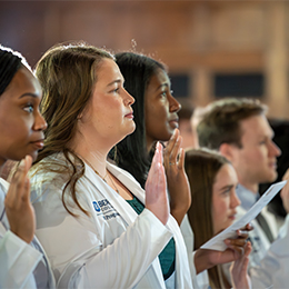 Group of students in white coats taking an oath