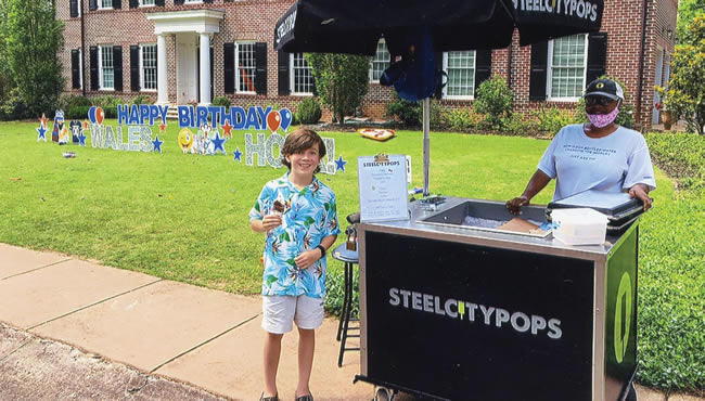 Male student with popsicle next to Steel City Pops stand