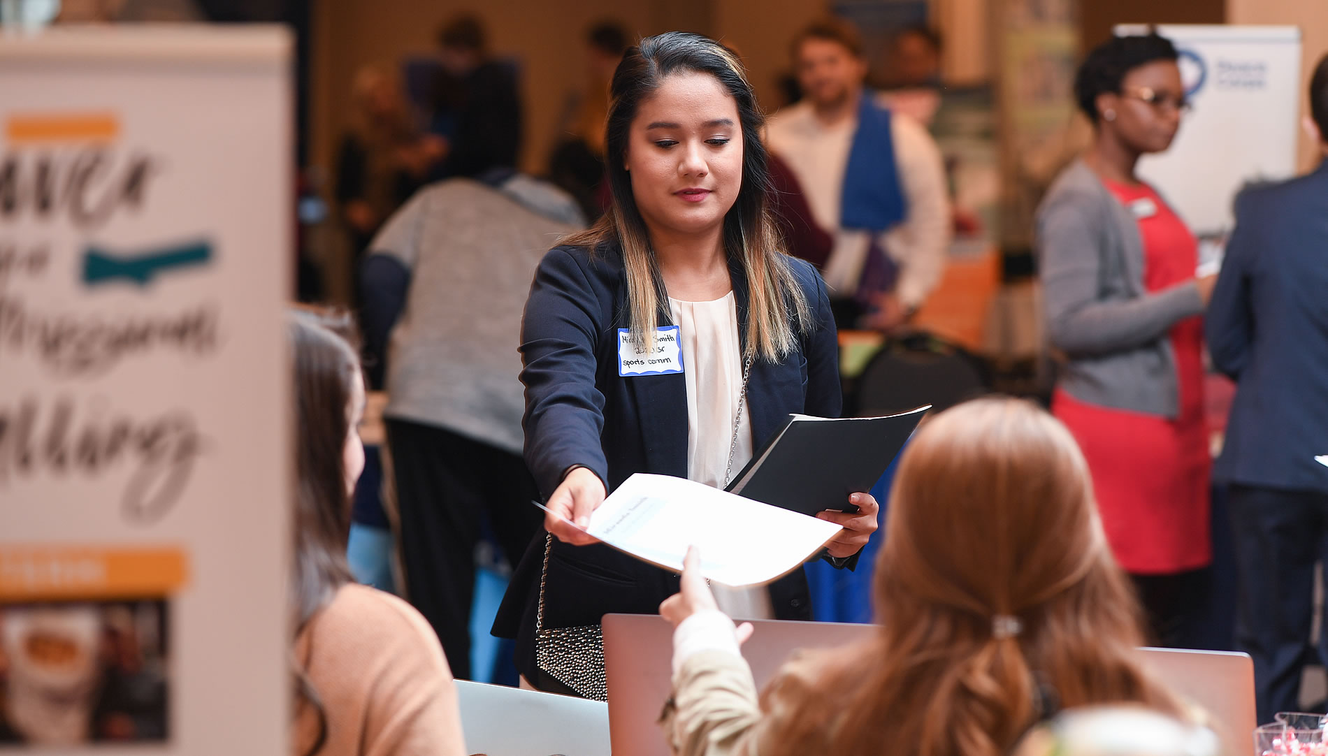 Student handing out resume to potential employers during a career fair