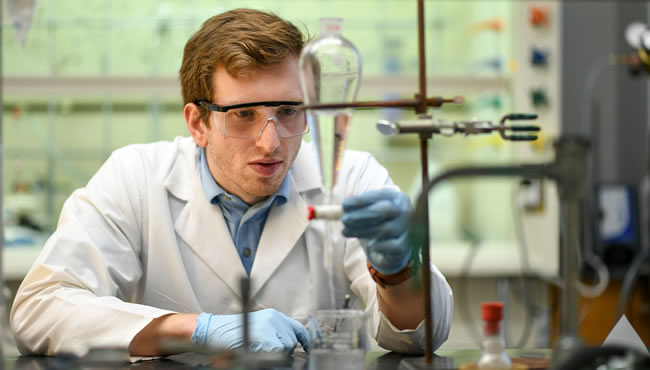 a male student measuring liquids and working in a laboratory