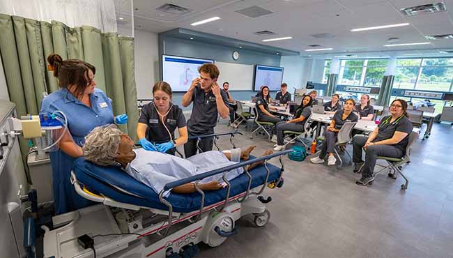 Class of nurses observing a live patient care simulation