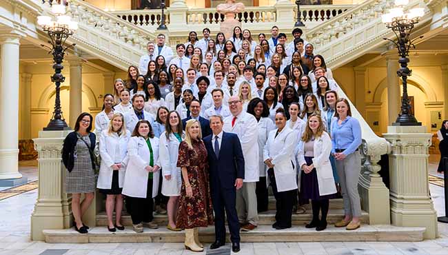 They Berry College Physician Associate Program students and faculty in white lab coats on the steps of the Capitol with the Governor and First Lady