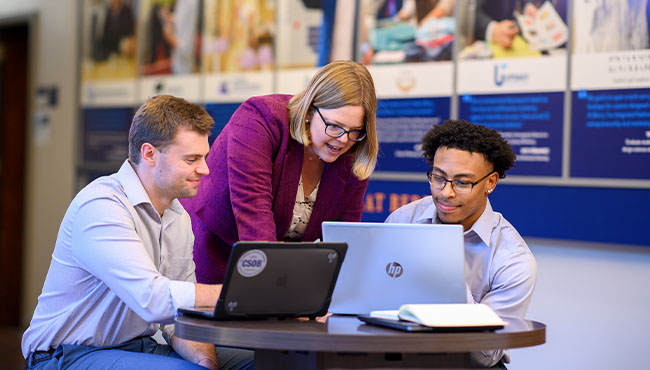 Female professor and two male students looking at a computer screen