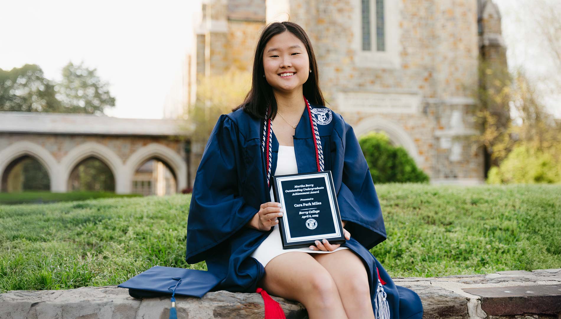 Cara Miles in her graduation robe, holding an award plaque