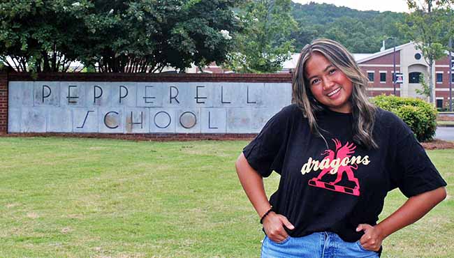 Gaile Anasco smiling in front of the Pepperell High School sign
