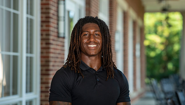 Oro Avery smiling outside in front of a brick building