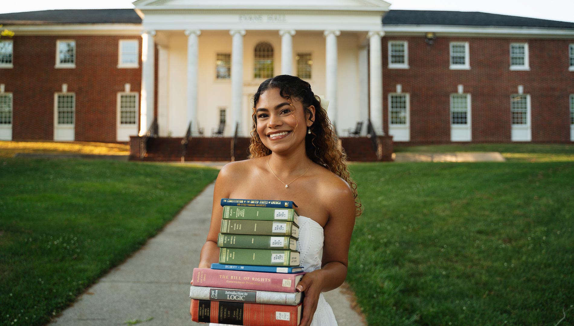 Yinia Hernandez smiling and holding a stack of law books