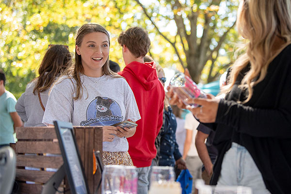 Female student smiling at a booth during a market