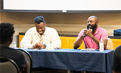 two males at a table for a talking panel